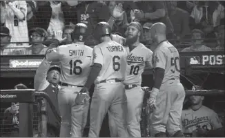  ?? Robert Gauthier Los Angeles Times ?? THE DODGERS’ Will Smith and Trea Turner celebrate with teammates after scoring on a tworun double by Cody Bellinger during the sixth inning of Game 2. Bellinger started at first base.