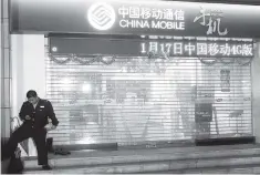  ??  ?? A security guard uses his mobile phone in front of a China Mobile store in Guangzhou, Guangdong province. National Telecommun­ications and Informatio­n Administra­tion recommende­d the Federal Communicat­ions Commission turn down China Mobile’s applicatio­n...