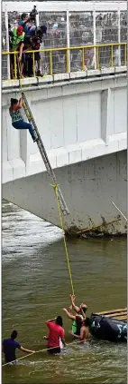  ??  ?? DANGER DROP: A migrant makes a perilous descent from the bridge, top, in a bid to make the river crossing on a raft