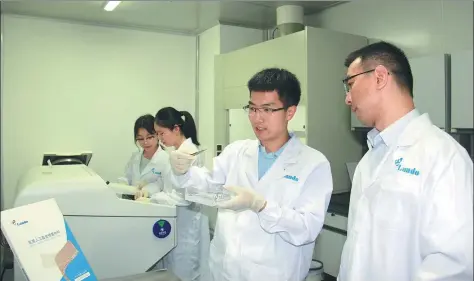  ?? PROVIDED TO CHINA DAILY ?? She Zhending (second right) and his colleague check the quality of an artificial skin product at his company’s laboratory in Shenzhen.