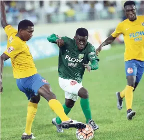  ??  ?? Excelsior High’s Tyane Wilson (centre) is stopped in his tracks by Clarendon’s College Tremaine Williams (left) during last Saturday’s FLOW Super Cup quarter-final match at Sabina Park.