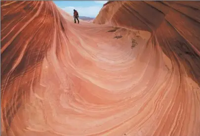  ?? The Associated Press ?? MONUMENTAL CHANGE: In this May 28, 2013, photo, a hiker walks on a rock formation known as The Wave in the Vermilion Cliffs National Monument in Arizona. Interior Secretary Ryan Zinke said he's recommendi­ng that none of 27 national monuments carved...
