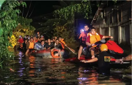  ?? AFP/GETTY IMAGES ?? Rescue workers guide flood-affected residents Saturday in Davao, on the island of Mindanao, after Tropical Storm Tembin dumped torrential rains.