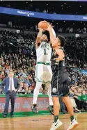  ??  ?? BRIAN BABINEAU/GETTY IMAGES Kyrie Irving (L) of the Celtics shoots the ball against the Bucks in an NBA game at TD Garden in Boston, MA, the US on November 1, 2018.