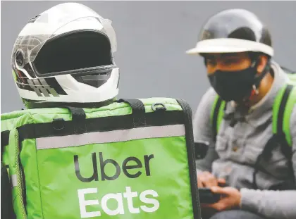  ?? VALENTYN OGIRENKO/REUTERS FILES ?? An Uber Eats food-delivery courier waits for an order in Kyiv in May. Consumers stuck at home have boosted that business globally by 52 per cent to US$4.68 billion in the first quarter. Uber is now turning to expanding grocery delivery service in Latin America.
