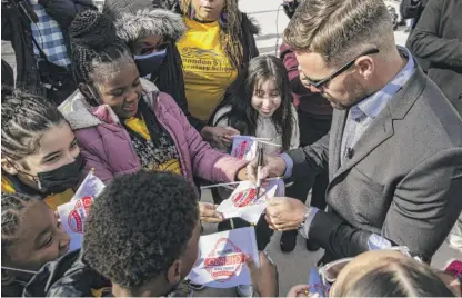  ?? ASHLEE REZIN/SUN-TIMES PHOTOS ?? ABOVE: Daytona 500 champion Ricky Stenhouse Jr. signs autographs for students outside the Field Museum on Tuesday. LEFT: Students from Wadsworth STEM Elementary School listen at the Field news conference promoting the NASCAR race.