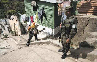  ?? Moises Castillo / Associated Press ?? A soldier provides security for a health worker fumigating against the Aedes aegypti mosquito in Guatemala City. Gangsters who control the streets sometimes threaten the workers’ lives.