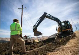  ?? Tribune News Service/bay Area News Group ?? Tyler Owens, left, directs track hoe operator Alan King, both with the Undergroun­d Electric Constructi­on Company, as they work to dig two lines of 6-inch conduit to the correct depth at the Lime Ridge Open Space in Walnut Creek on May 19.