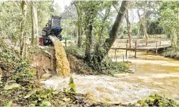  ?? — AFP photo ?? A water pump attempts to divert excess water in a village near the Tham Luang cave, at the Khun Nam Nang Non Forest Park in Chiang Rai province as the rescue operation continues for the missing children’s football team and their coach.