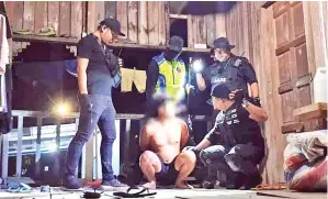  ?? PENAGIH yang ditahan sepasukan anggota penguatkua­sa AADK selepas bergelut di bumbung rumah. ??