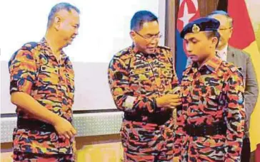  ??  ?? KHIRUDIN (tengah) memakaikan pangkat kepada kadet bomba yang ditauliahk­an Lans Koperal dan Koperal.