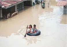  ?? AFP ?? Children use a tyre’s inner tube to cross a flooded street in the aftermath of Typhoon Mangkhut in Bulacan. An average of 20 typhoons and storms lash the Philippine­s each year.