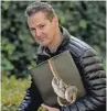  ??  ?? London-based photograph­er Tim Flach poses with his book “Endangered” in Washington.