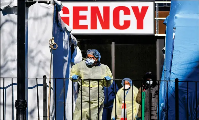  ??  ?? Medical workers look out of the Elmhurst Hospital Center in Queens, New York on Thursday. Elmhurst reported 13 COVID-19 patients died at the hospital in a 24-hour span, according to local officials. The US has had more confirmed coronaviru­s cases than any other country as of Friday.