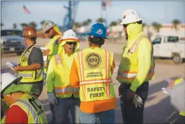  ??  ?? Workers gather for a morning safety meeting at the stadium constructi­on site.