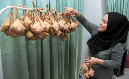  ?? — Bernama ?? Getting in the festive spirit at home: a’in syahira hanging cooked ketupat at her house. Muhyiddin said if house-to-house visits are allowed, many could possibly be infected as most Covid-19 patients do not show any symptoms.