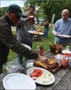  ?? (Arkansas Democrat-Gazette/Bryan Hendricks) ?? Bill Eldridge Jr. of Benton, Matthew Eldridge of Dallas (middle) and Bill Eldridge Sr. of Little Rock enjoy a shore lunch prepared by their guides Craig Yowell and Doug Knight on Monday on the White River at Rim Shoals.