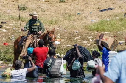  ?? Paul Ratje, AFP via Getty Images ?? A United States Border Patrol agent on horseback uses the reins as he tries to stop Haitian migrants from entering an encampment on the banks of the Rio Grande near the Acuna Del Rio Internatio­nal Bridge in Del Rio, Texas on Sept. 19.