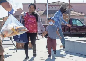  ??  ?? A person hands a bag filled with pasta, rice and other essentials to a mother and her son at a food distributi­on event in Salinas,Calif., last month. Food banks are worried about keeping the needy fed amid the coronaviru­s pandemic.