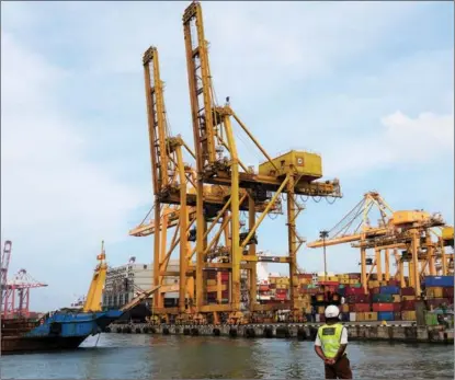  ?? TANG LU / XINHUA ?? A worker observes constructi­on at a harbor in Colombo, Sri Lanka, commission­ed by China Harbour Engineerin­g Co Ltd on Dec 1.