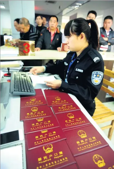  ?? ZHANG JIANCHENG / FOR CHINA DAILY ?? A police officer helps applicants to change their household registrati­on informatio­n in Wuyi county, Zhejiang province, after the county scrapped the distinctio­n between rural and urban in April.