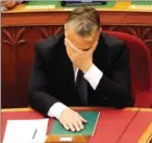  ?? ATTILA KISBENEDEK/AFP ?? Hungarian Prime Minister Viktor Orban covers his face in parliament yesterday.