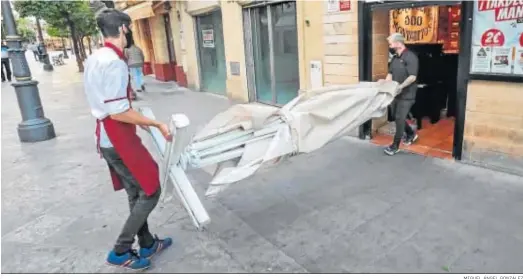  ?? MIGUEL ÁNGEL GONZÁLEZ ?? Camareros de un bar del centro de Jerez retirando ayer una sombrilla antes del cierre.