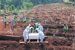  ??  ?? Workers wearing protective suits bury a coffin in the Muslim burial area provided for victims of the coronaviru­s disease at Pondok Ranggon cemetery in Jakarta.