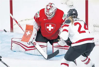  ?? JEFF MCINTOSH THE CANADIAN PRESS ?? Switzerlan­d’s goalie Andrea Braendli, left, deflects a shot from Canada’s Natalie Spooner on Tuesday in Calgary.