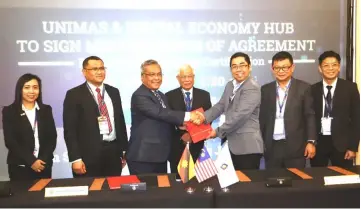  ??  ?? Mohamad Kadim (third left) shakes hands with Ling as they exchange documents in the presence of others after the MoA signing. At centre is Manyin.