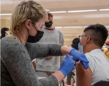  ?? BoSton herald file ?? GETTING VACCINATED: Registered nurse Katrina Rosenberg administer­s the first dose of Pfizer’s coronaviru­s vaccine to Douglas Landaverde, 15, of Everett at the Cambridge Health Alliance vaccinatio­n clinic at Everett High School on Aug. 30.