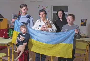  ?? AP PHOTO/EVGENIY MALOLETKA ?? Natalia Zhyvohliad, center, an internally displaced person from Nova Petrivka in the Zaporizhzh­ia region of Ukraine, poses with some of her children Jan. 19 at the IDP shelter in Kyiv.