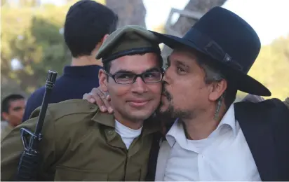  ??  ?? A SOLDIER and his relative celebrate at a haredi brigade swearing-in ceremony.