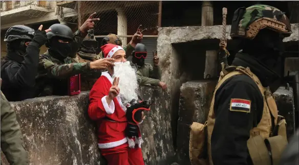  ??  ?? Santa Claus proves a popular figure in Baghdad as Iraqi security forces crowd round him to take pictures during protests. Activists want the government to quit and hold early elections