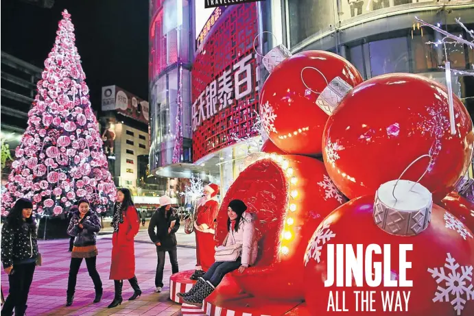  ?? Picture: Feng Li/Getty Images ?? OH WHAT FUN Shoppers pose with Christmas decoration­s in front of a mall in Beijing, China. The holiday continues to gain traction in that country’s consumer culture.