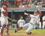  ?? TONY DEJAK ASSOCIATED PRESS ?? The Reds’ Joey Votto, right, scores as Indians catcher Roberto Perez watches during Tuesday’s game in Cleveland. The Reds won 7-4.