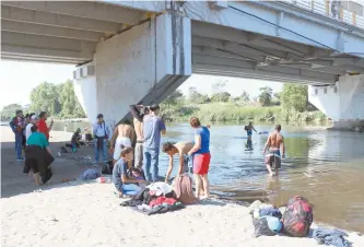  ??  ?? Abajo del Puente Internacio­nal Rodolfo Robles decenas de migrantes se bañan y lavan la ropa en las aguas del río Suchiate, como el hondureño Jehovay y sus hijos, quienes huyeron de su país debido a la insegurida­d.