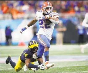  ?? Joe Robbins / Getty Images ?? Florida’s Lamical Perine escapes the tackle attempt of Michigan’s Josh Metellus and runs for a fourth-quarter touchdown during the Chick-fil-A Peach Bowl on Saturday.
