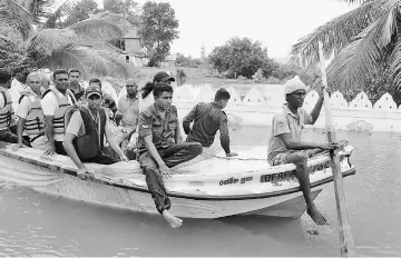  ??  ?? Sri Lankan villagers being evacuated through floodwater­s in Nagoda in Kalutara district. — AFP photo