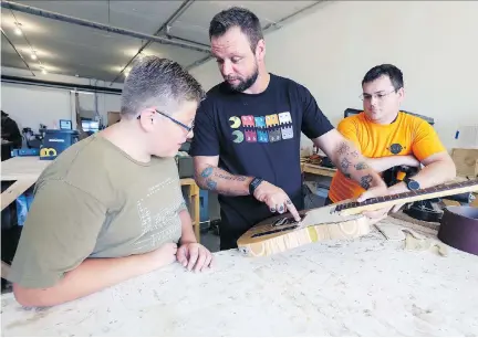  ?? JOHN MAHONEY ?? Musician James Klym talks to his son and another workshop participan­t about the electric guitar he built out of wood from skateboard­s. Klym teaches guitar-making and gives courses on playing the instrument at the Atelier Helios Makerspace.