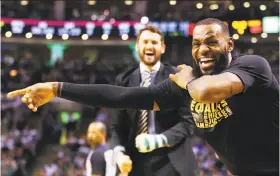  ?? Adam Glanzman / ?? LeBron James exults in the second half, with injured teammate Kevin Love behind, in the Cavs’ 121-99 win in Boston. Fans endured the rout as they awaited Paul Pierce’s jersey retirement after the game.