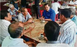  ??  ?? Catching up: Sazali (in blue) enjoying a cup of coffee with his friends at Kampung Paya Rumput in Melaka.