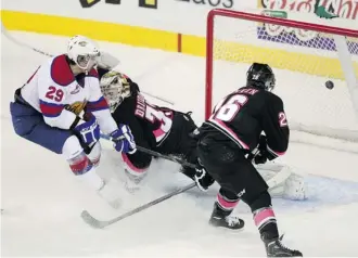  ?? Colleen De Neve/Calgary Herald ?? Edmonton Oil Kings left winger Mitchell Moroz tips the puck past Calgary Hitmen goalie Chris Driedger and left winger Connor Rankin Sunday during overtime at the Scotiabank Saddledome.