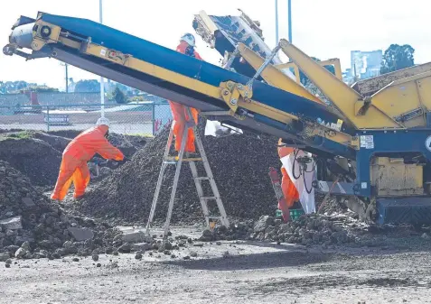  ?? Picture: GLENN FERGUSON ?? HIGH ALERT: Workers remove asbestos from a soil mound at the southern end of the West Oval precinct.