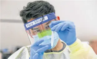  ?? TIM KROCHAK • THE CHRONICLE HERALD ?? Roman Pruski works on patient samples at a rapid testing site at Central Spryfield School in Halifax in May.