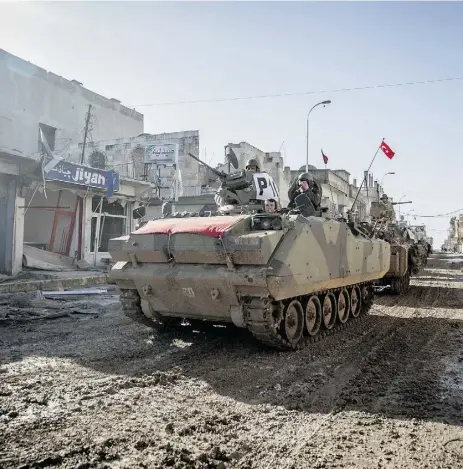  ?? Mursel Coban , Depo Photos / The Associat ed Press ?? Turkish armoured vehicles and tanks drive through the Syrian town of Ayn al-Arab on Feb. 22.