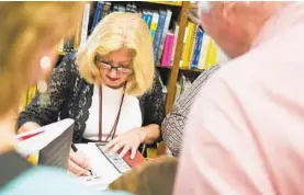  ?? JOSHUA MCKERROW/CAPITAL GAZETTE ?? At an event at Politics and Prose in Washington, Andrea Chamblee signs a copy of “The Capital of Basketball,” written by her husband, John McNamara.