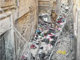  ?? THE ASSOCIATED PRESS ?? An Iraqi special forces soldier walks on clothes left in an alley Wednesday by fleeing civilians as Iraqi forces continue their advance against Islamic State militants in the Old City of Mosul, Iraq.