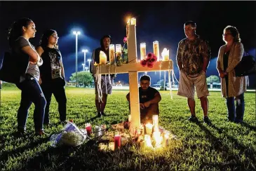  ?? GREG LOVETT / THE PALM BEACH POST ?? People visit one of 17 crosses following a candleligh­t vigil for the victims of the shooting at Marjory Stoneman Douglas High School, in Parkland, Fla., Thursday.