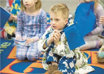  ?? KYLE TELECHAN/POST-TRIBUNE ?? St. Paul kindergart­ners, dressed in pajamas to celebrate Catholic Schools Week, hold blue flags to celebrate the school’s blue ribbon accreditat­ion Monday.